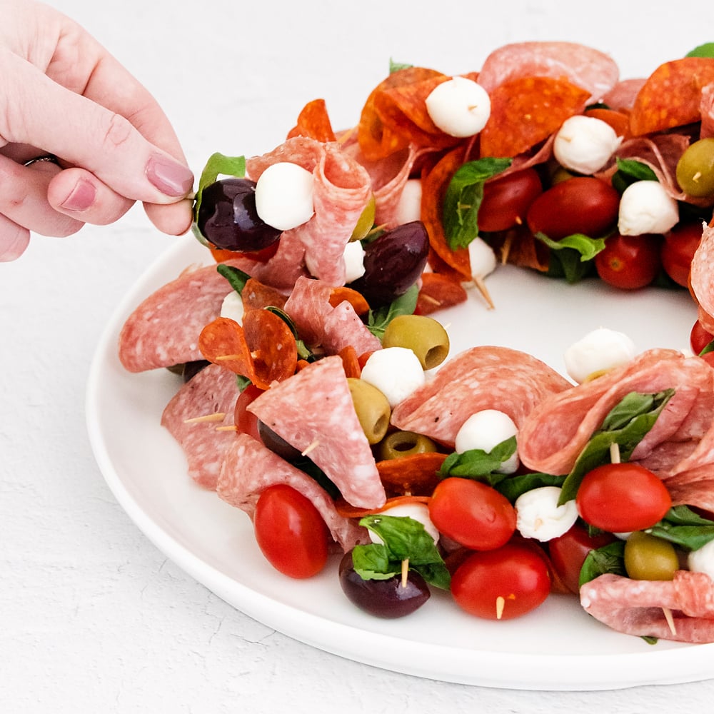 christmas wreath appetizer on plate with skewers of meat and cheese