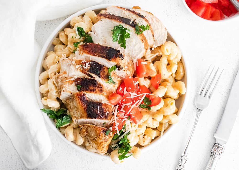 cajun chicken breasts sliced over alfredo pasta topped with tomatoes and parsley