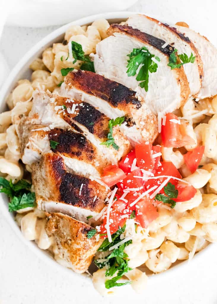 cajun chicken breasts sliced over alfredo pasta topped with parmesan and tomatoes