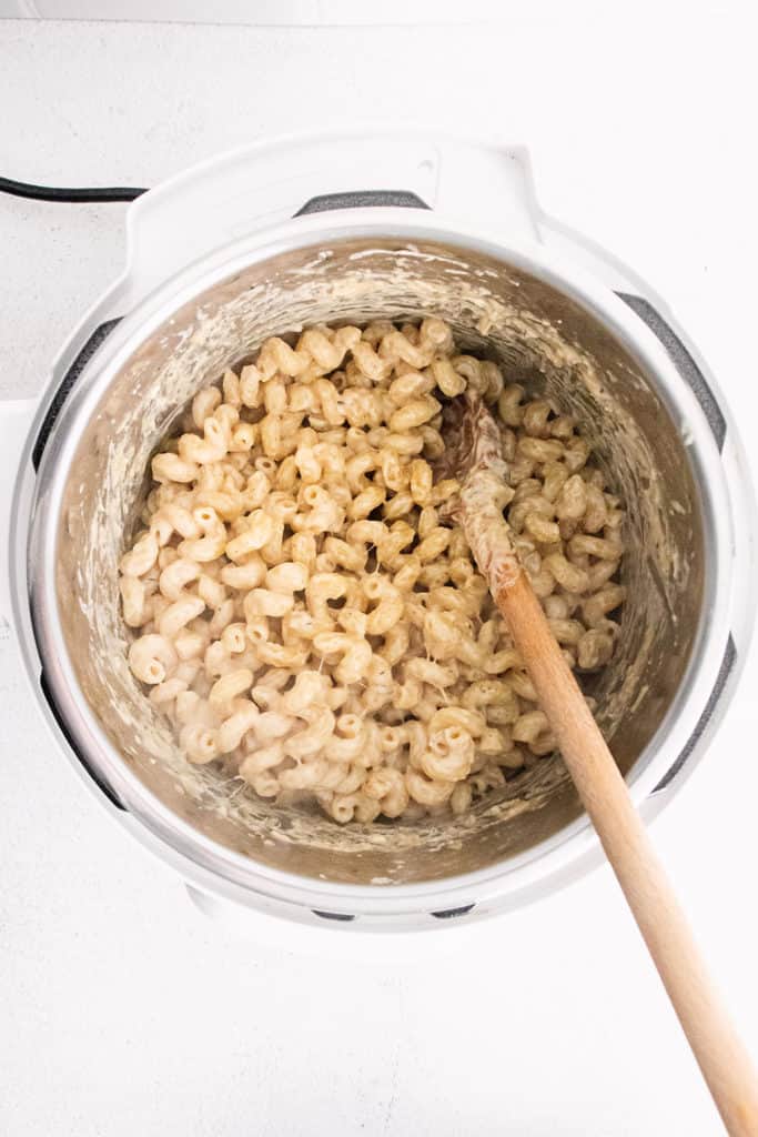 creamy alfredo pasta in an electric pressure cooker with wooden spoon