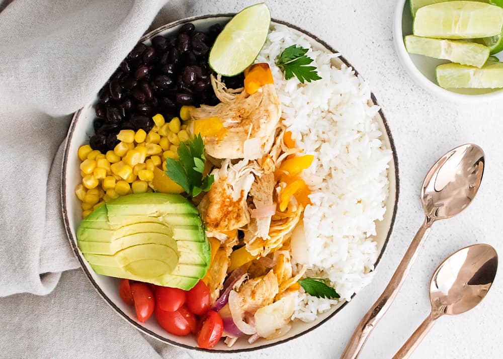 pressure cooker chicken fajita bowls on table with spoons and lime wedges