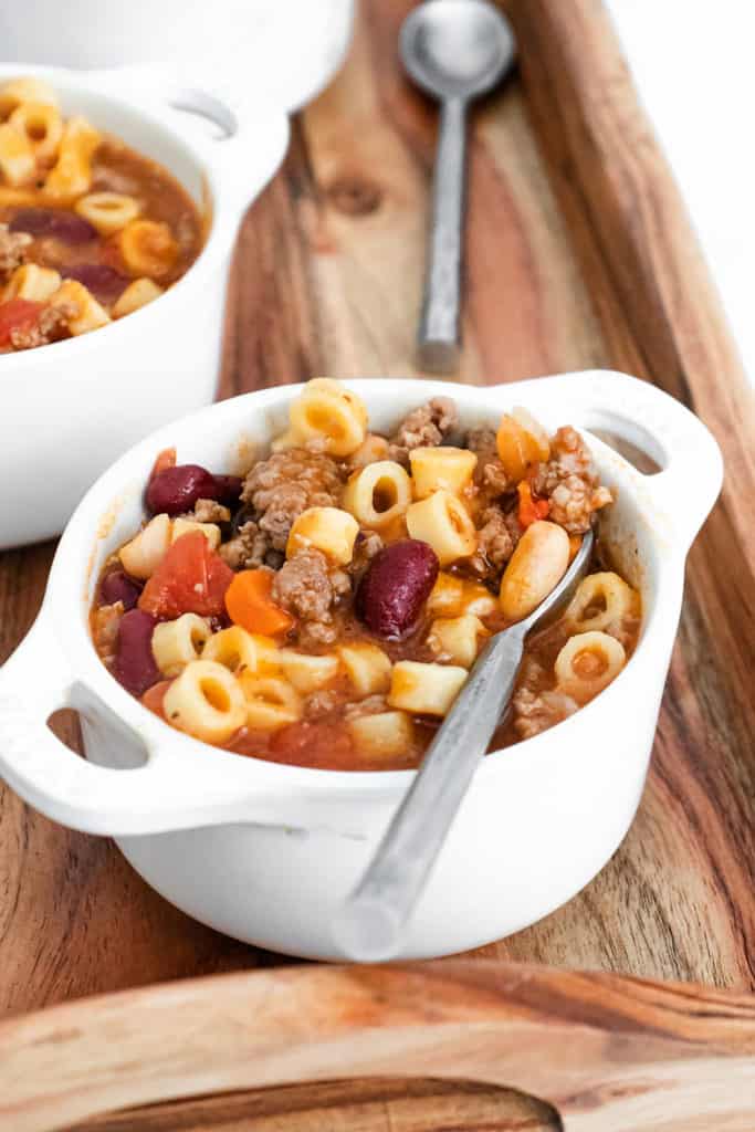 spoon scooping pasta e fagioli from white soup bowl