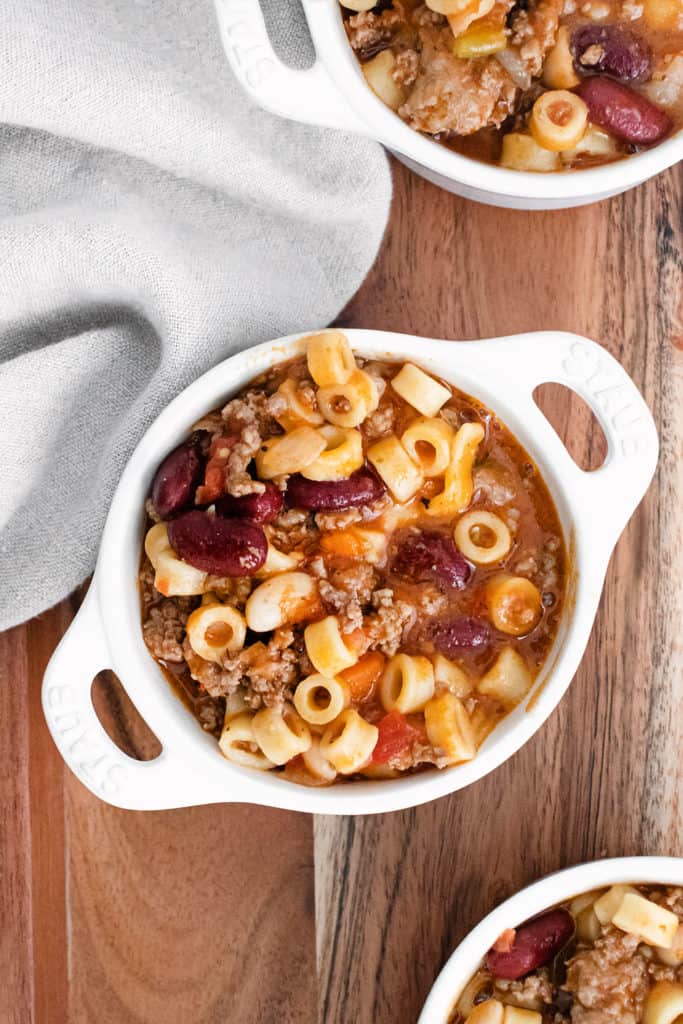 white bowls filled with pasta e fagioli soup on wooden tray with cloth napkin