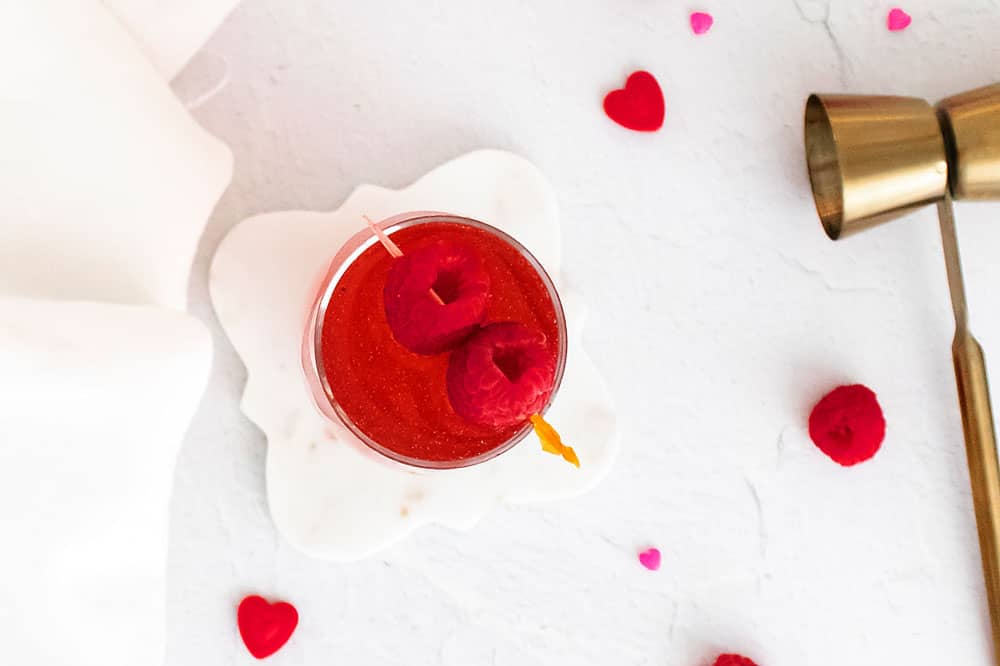 Raspberry Rosé Spritzer in clear glass with raspberries on toothpick