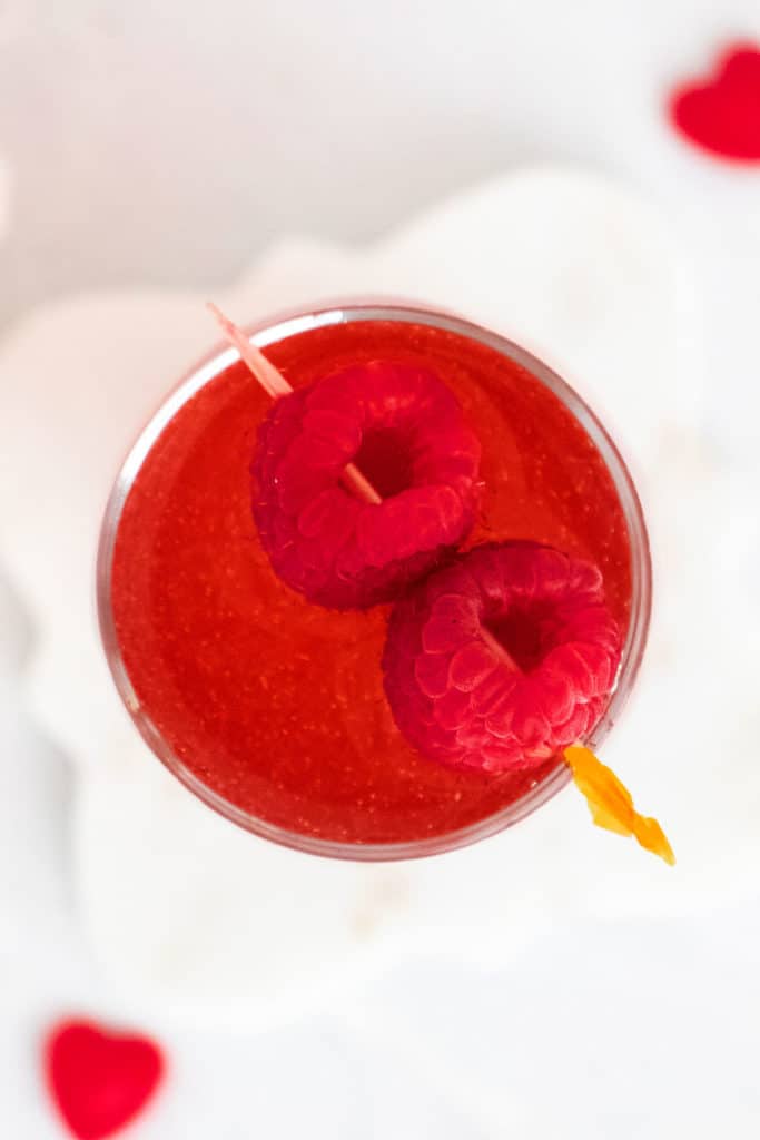 Raspberry Rosé Spritzer in clear glass with raspberries on toothpick