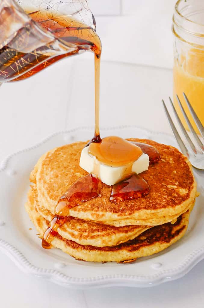 syrup being poured on cornmeal pancakes