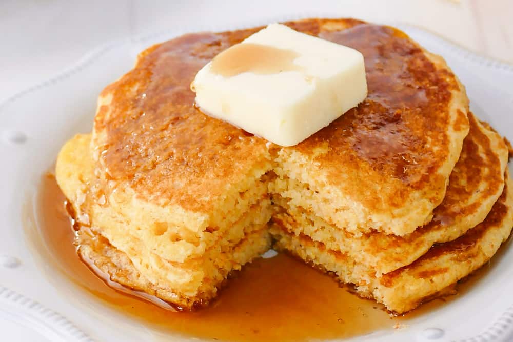 cornmeal pancakes topped with butter and syrup and bite taken out