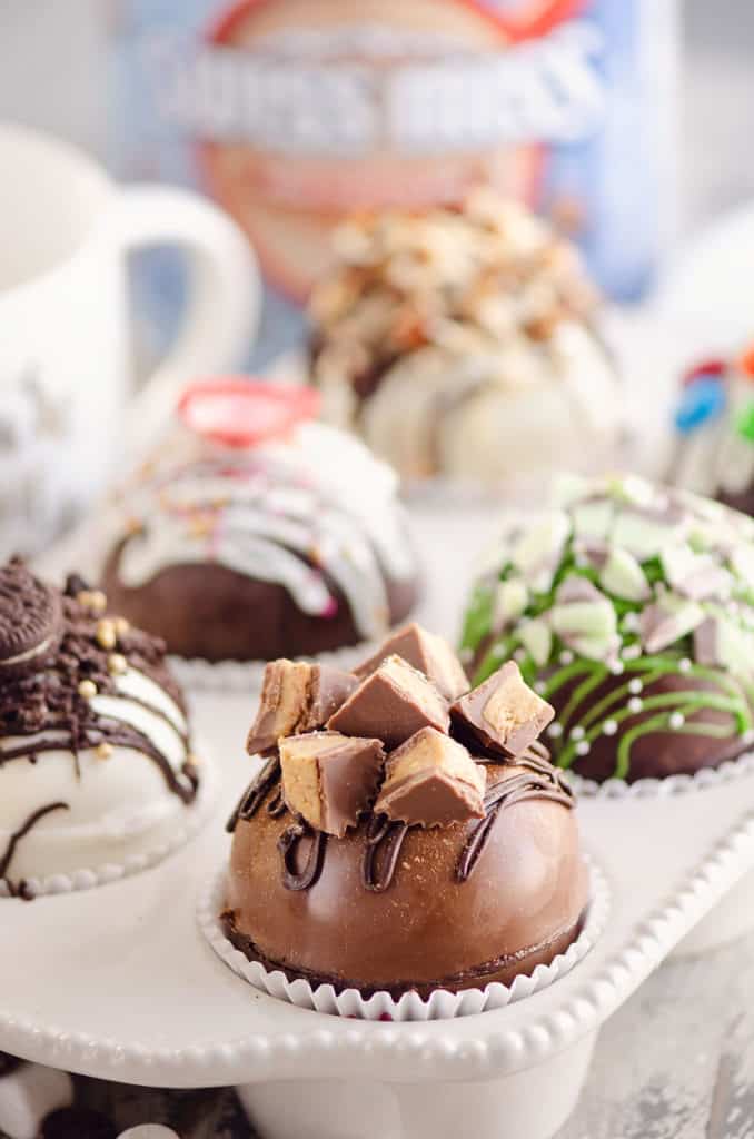 variety of hot cocoa bombs in muffin tin with hot chocolate mix