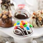 variety of hot cocoa bombs in muffin tin with hot chocolate mix