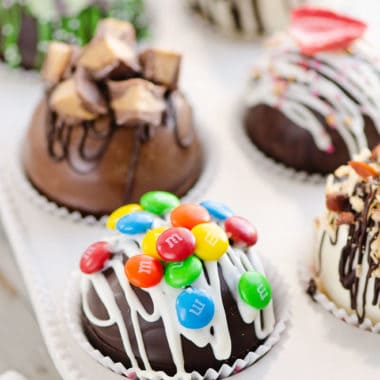 variety of hot cocoa bombs in muffin tin with hot chocolate mix