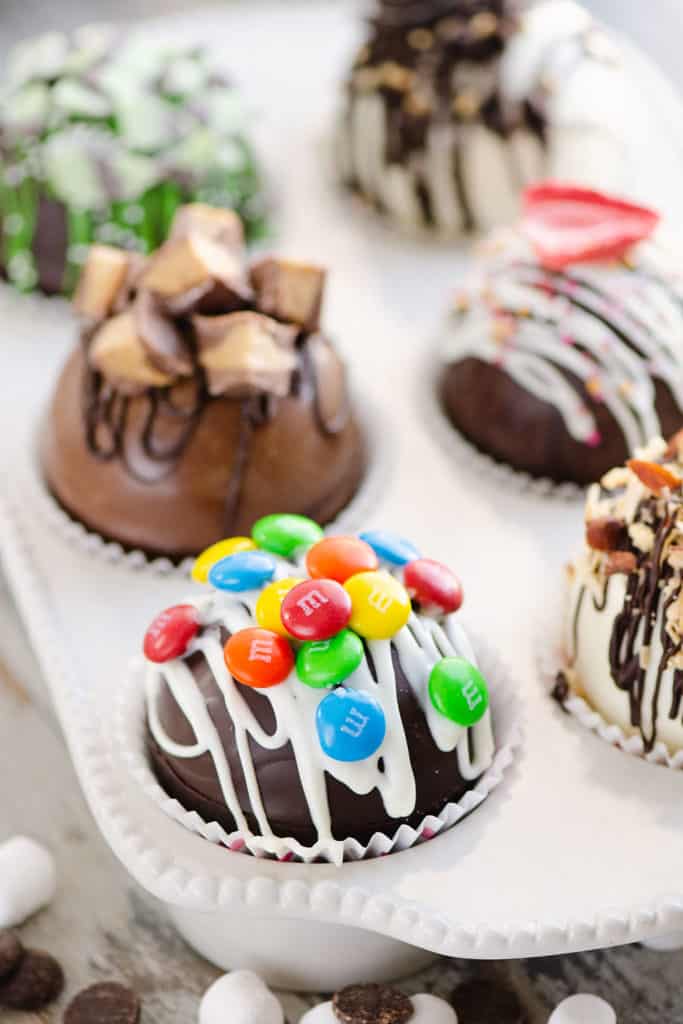 variety of hot cocoa bombs in muffin tin with hot chocolate mix