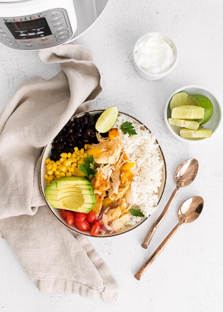 Instant pot chicken fajitas in white bowl on table with pressure cooker