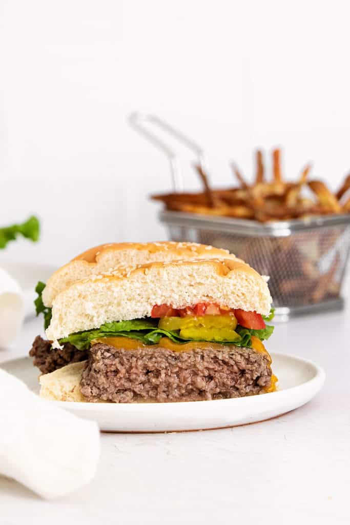 half of air fryer cheeseburger on plate with fries