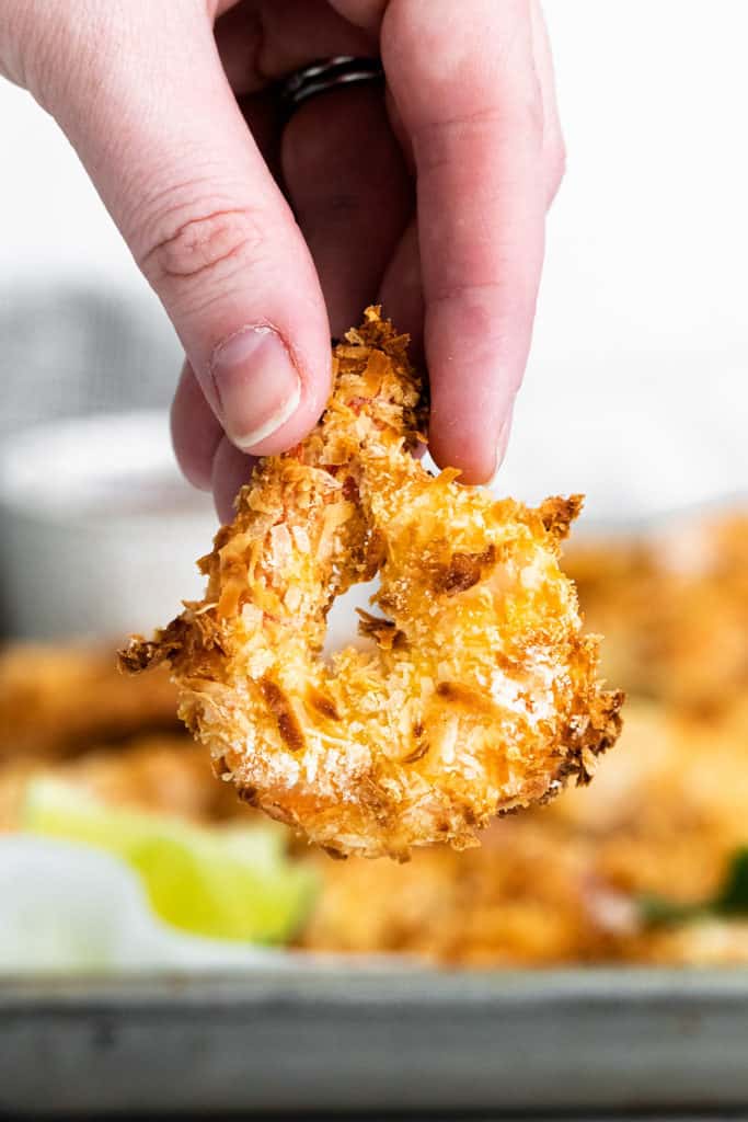 coconut shrimp being held in hand by tail
