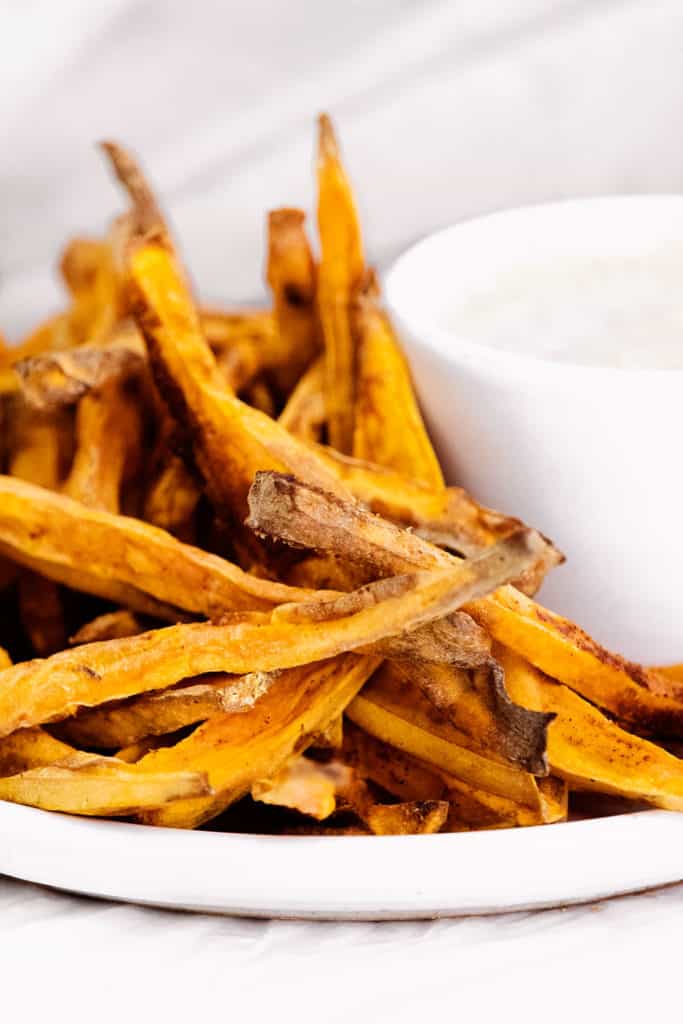 sweet potato fries on white plate with yogurt dipping sauce