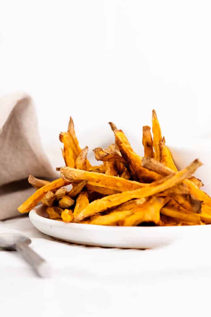 sweet potato fries on white plate with yogurt dipping sauce