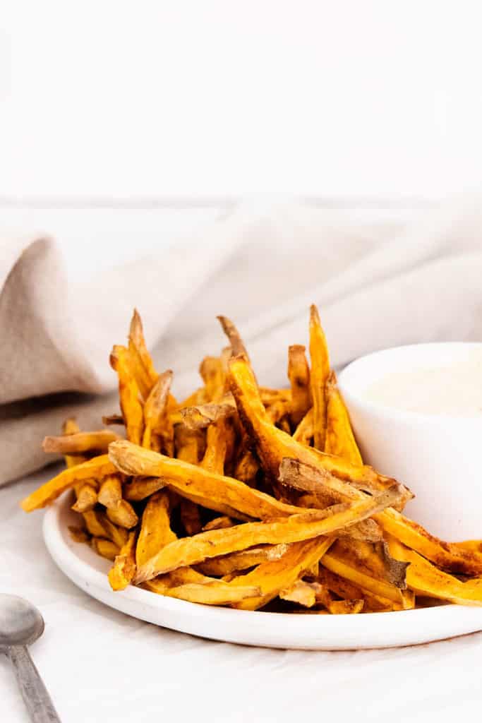sweet potato fries on white plate with yogurt dipping sauce