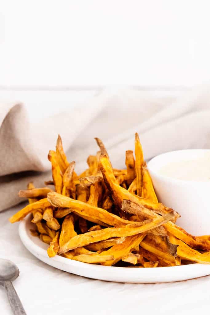 sweet potato fries on white plate with yogurt dipping sauce