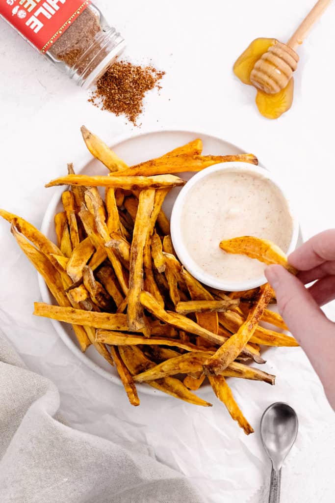 sweet potato fries being dipped into yogurt dipping sauce