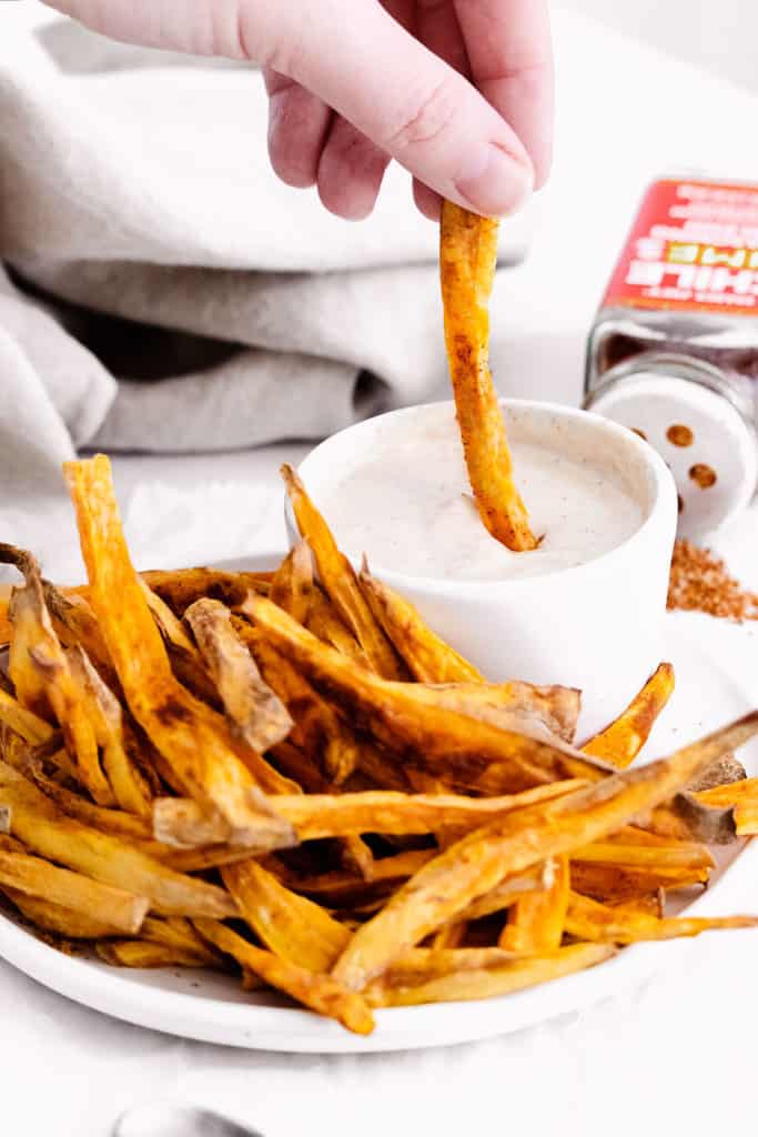 sweet potato fries being dipped into yogurt dipping sauce