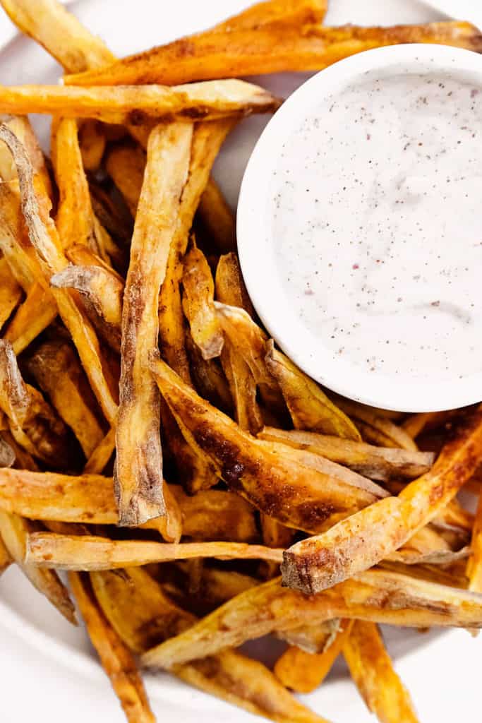 sweet potato fries on white plate with yogurt dipping sauce