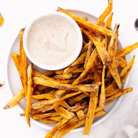 sweet potato fries on white plate with yogurt dipping sauce