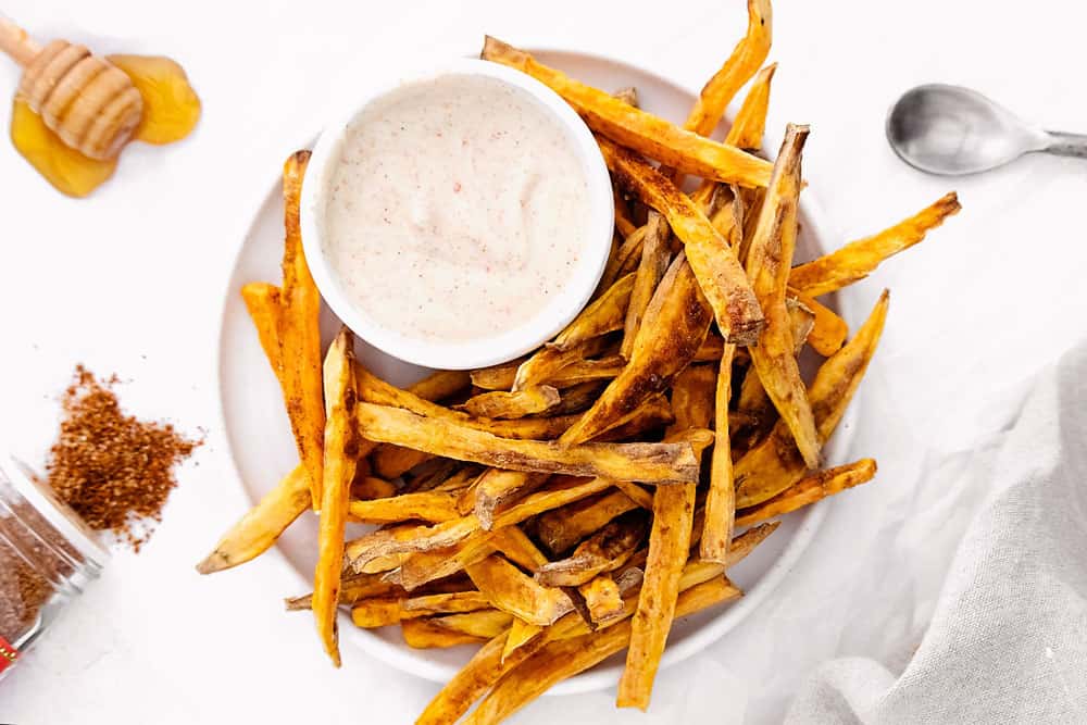 sweet potato fries on white plate with yogurt dipping sauce
