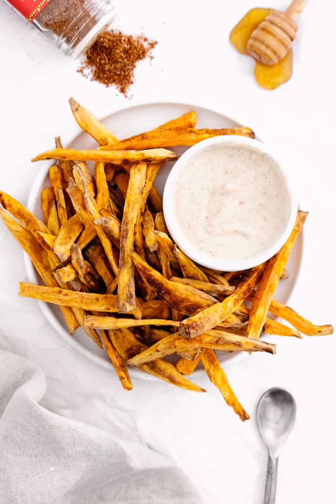 sweet potato fries on white plate with yogurt dipping sauce