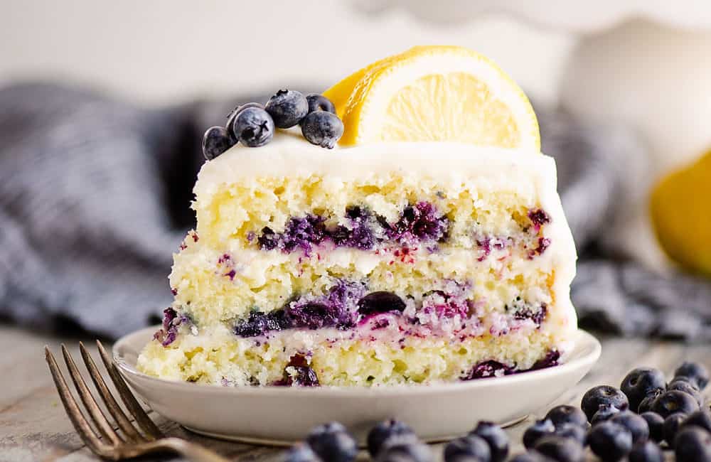 slice of lemon cake on plate with blueberries on table