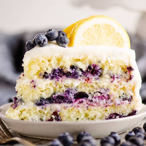 slice of lemon cake on plate with blueberries on table