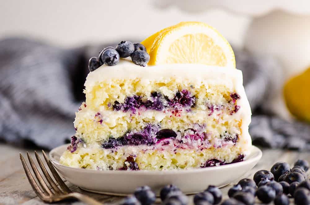 slice of lemon cake on plate with blueberries on table