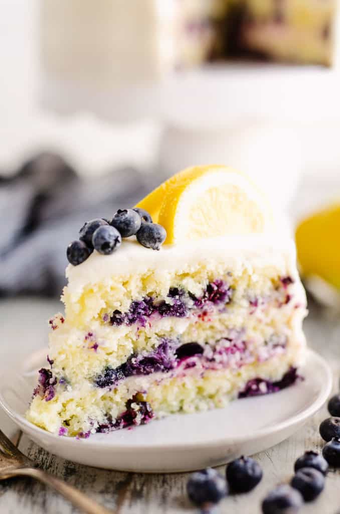 slice of blueberry cake on plate topped with lemons