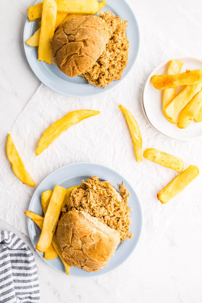 pulled pork sandwiches on plates with homestyle fries