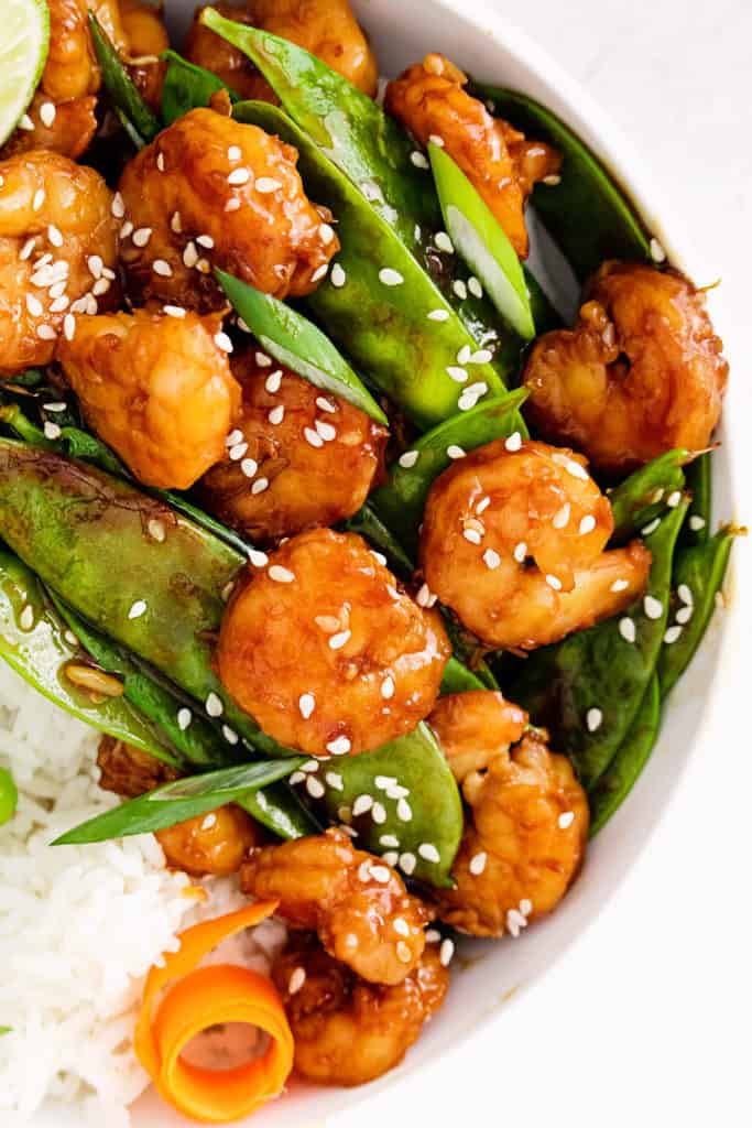 sesame shrimp, carrots and peas in white bowl