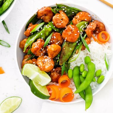 edamame, carrots, rice, lime, peas and shrimp in bowl with chopsticks
