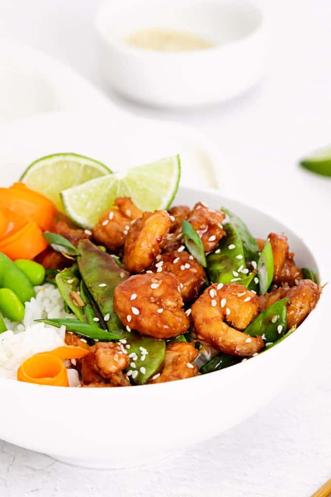 sesame shrimp, peas and carrots in white bowl