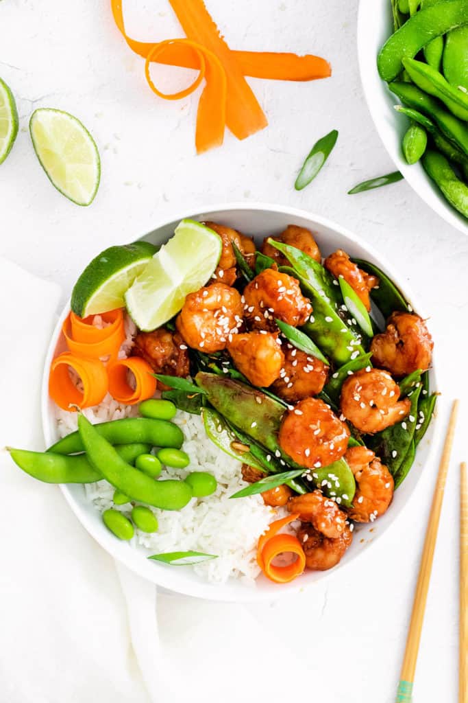 sesame shrimp bowls on whtie table with chopsticks and napkin