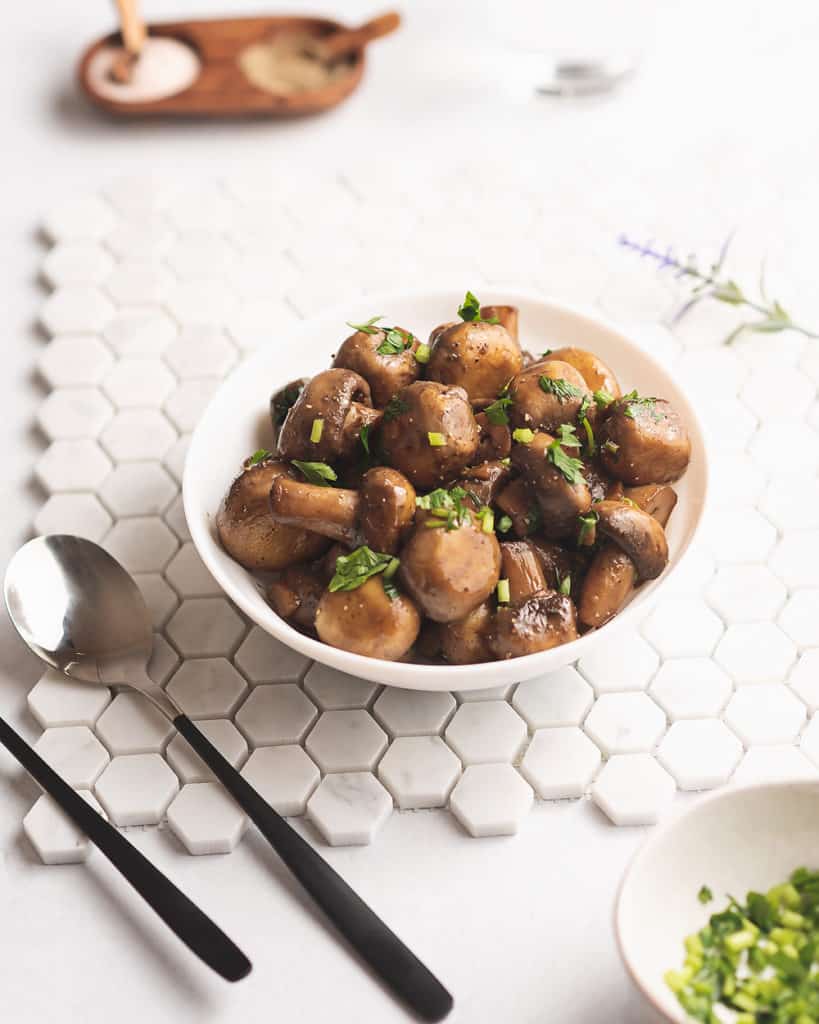 sauteed mushrooms on table with tile and utensils