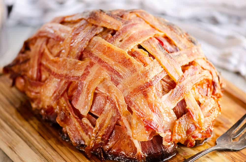 glazed bacon wrapped ham on cutting board
