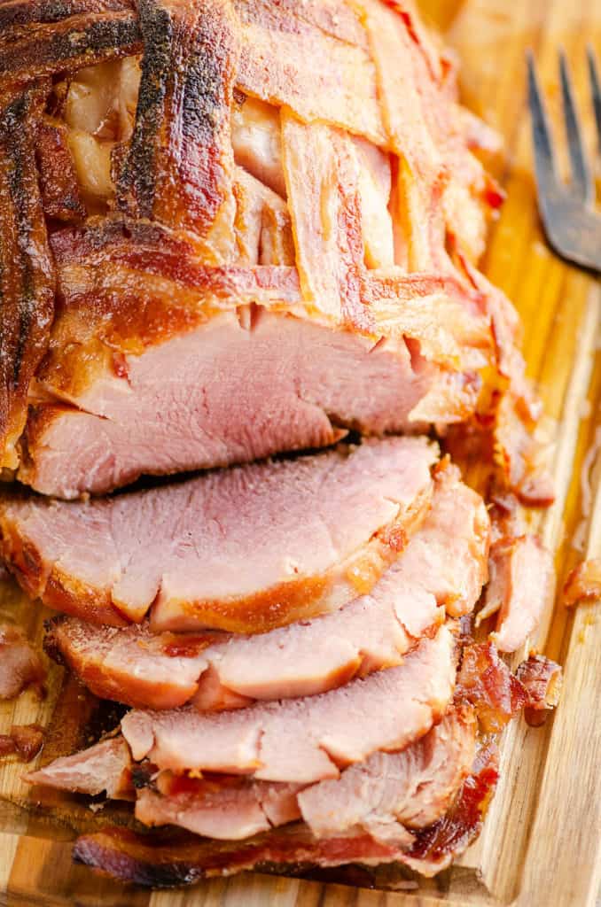 slices of bacon wrapped ham on cutting board with serving fork