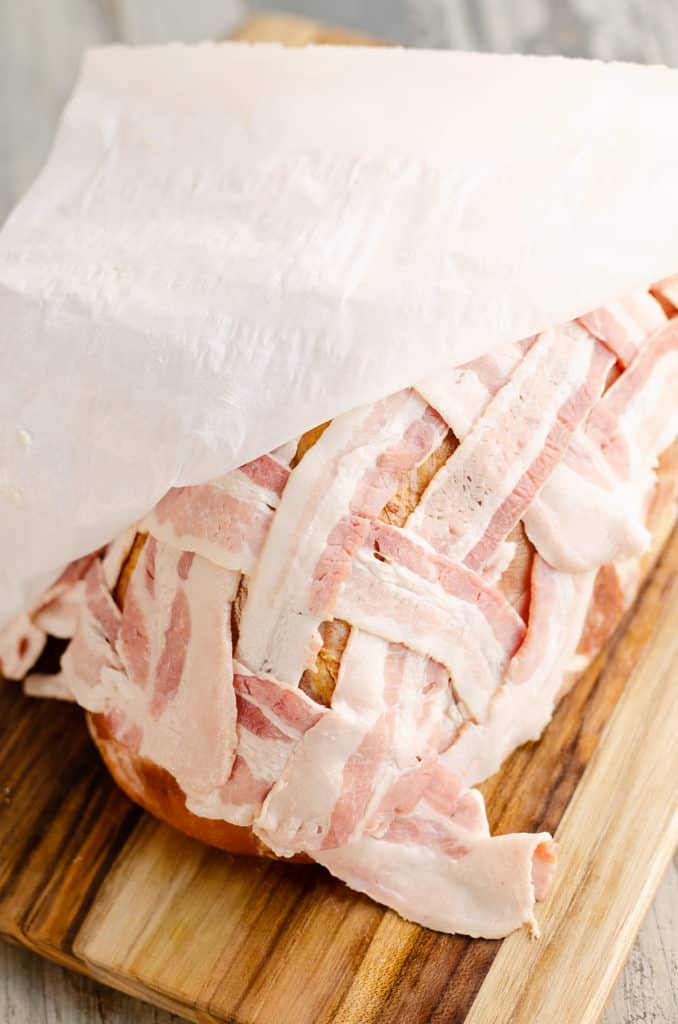 placing bacon lattice over ham with parchment paper