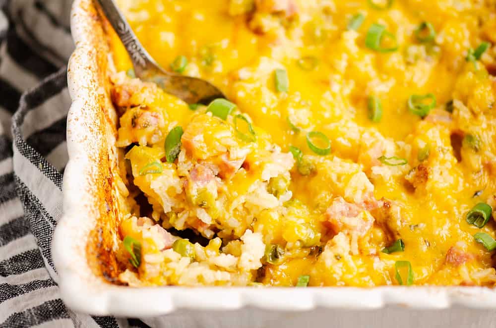 cheesy ham casserole with spoon scooping out ingredients