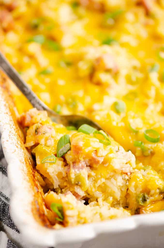 spoon scooping out ham and rice bake out of casserole dish