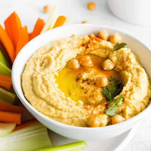 creamy classic hummus in white bowl topped with chickpeas