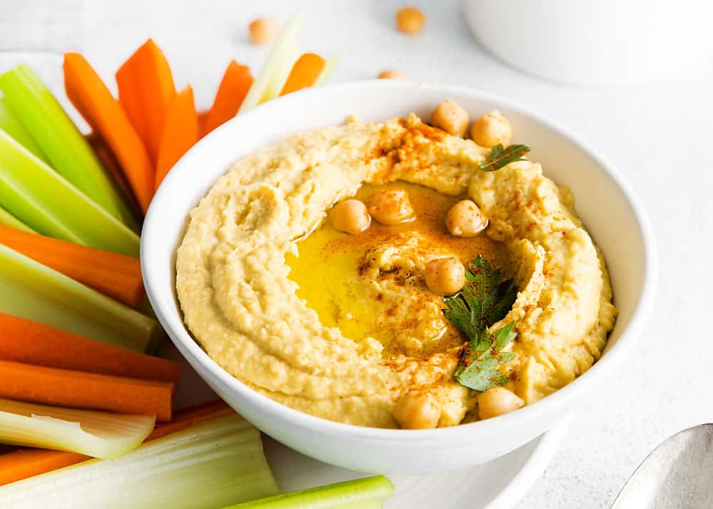 creamy classic hummus in white bowl topped with chickpeas