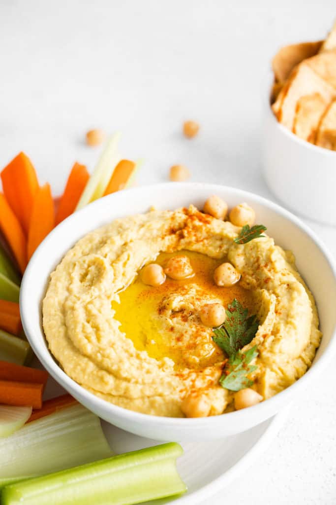 classic hummus in bowl served with carrots and celery