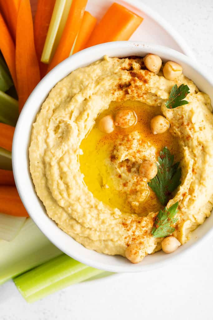white bowl of hummus topped with drizzle of olive oil
