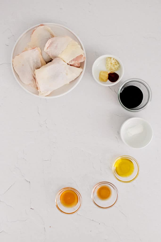 chicken thighs and ingredients in bowls on table