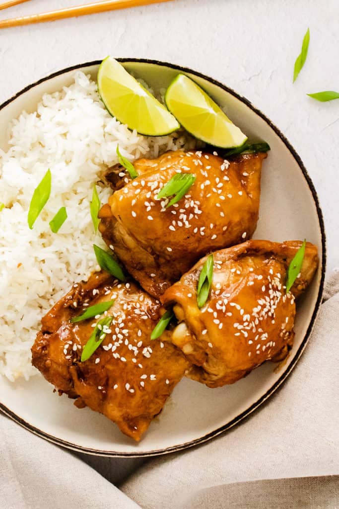 honey soy glazed chicken thigh in bowl garnished with sesame seeds and green onions