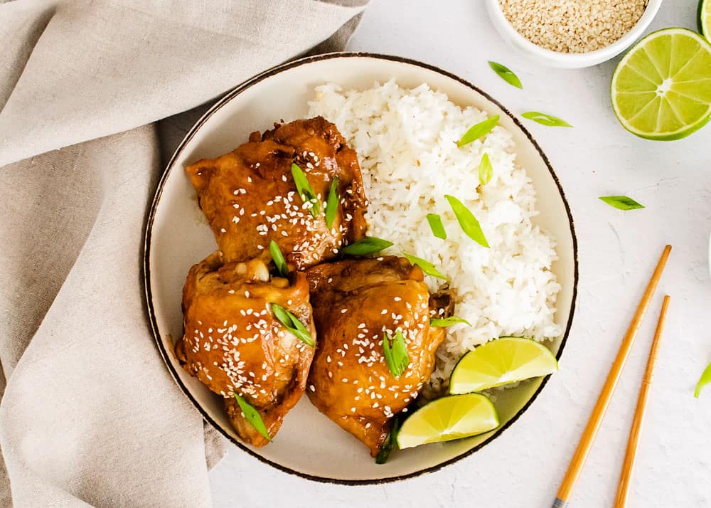 honey soy glazed chicken thighs in bowl with rice on table with chopsticks